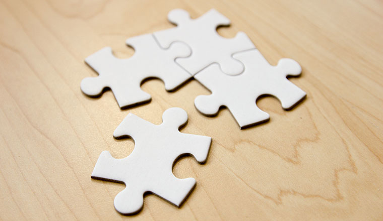 Four white puzzle pieces fit together on a wooden surface