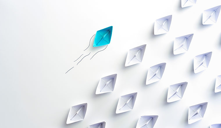 Blue paper ship are different from others and group of paper ships in one direction.