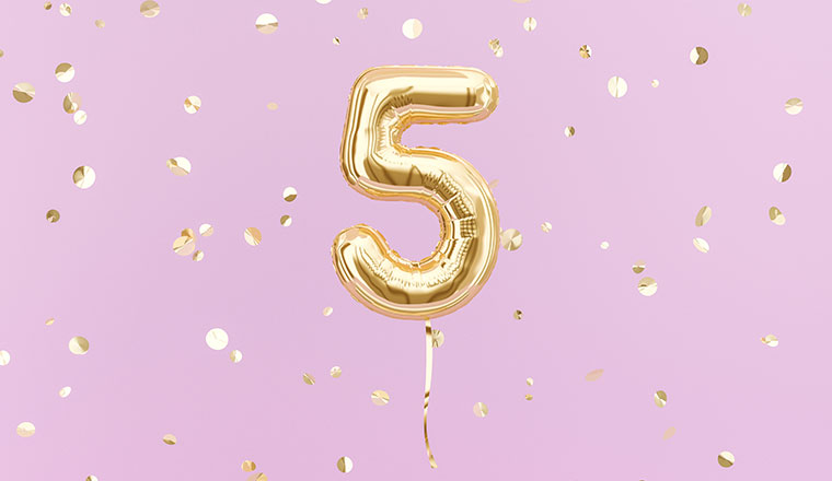 A photo of a gold balloon in the shape of the number 5