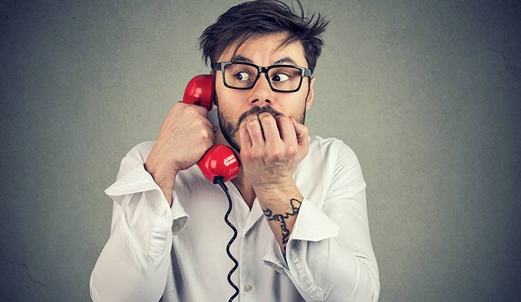 A picture of a person looking nervous on the telephone