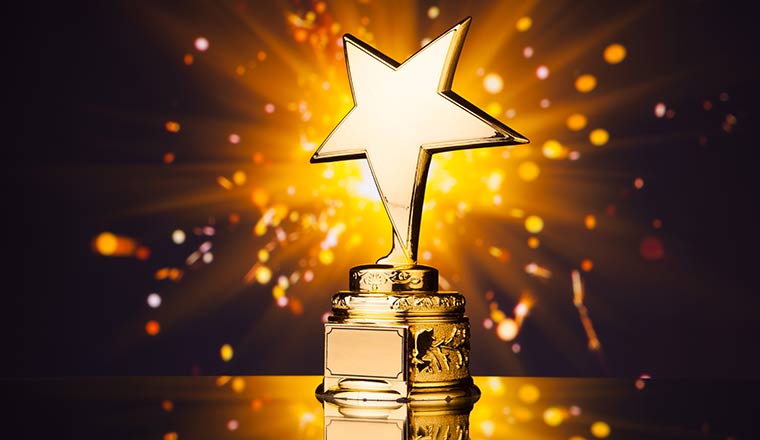 A gold star trophy against shiny sparks backgroun