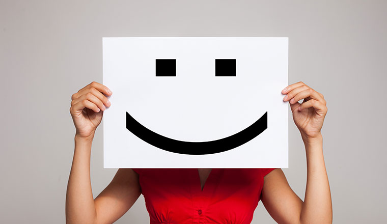 Person holding a smiley face on piece of paper