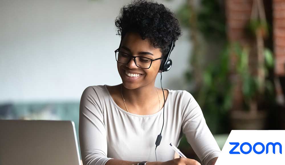 Smiling person on laptop making notes
