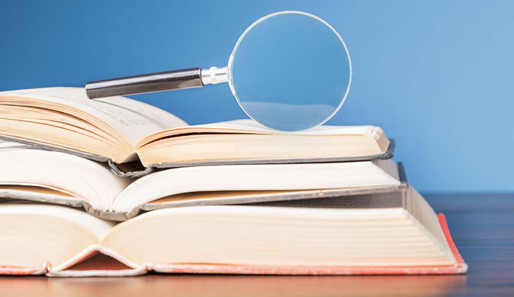 Stacked books with magnifying glass