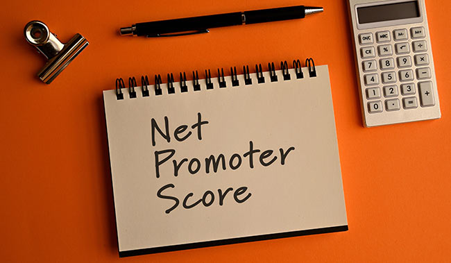 Net promoter score word written on a notepad and orange background