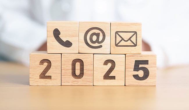 2025 in wood blocks with a call centre phone in a wooden block, an @ symbol and a email symbol