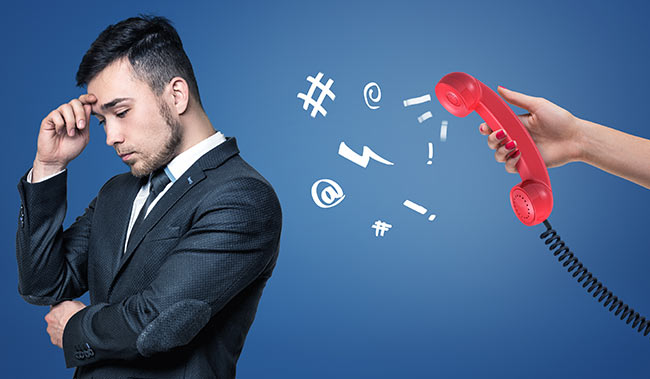 A tired businessman stands turned away from a red retro phone