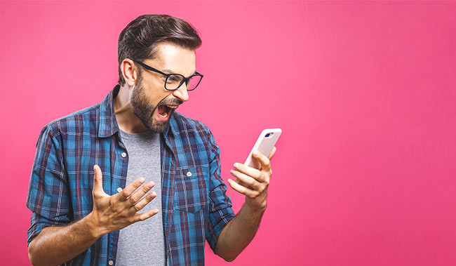 Person looking angry at their phone with a pink background
