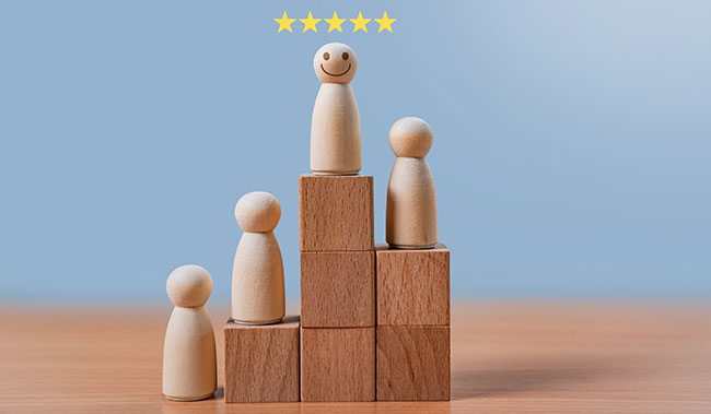 A smiling wooden figure stands on the highest block with a five-star rating above.