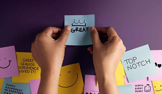 Happy customers putting post it notes on wall