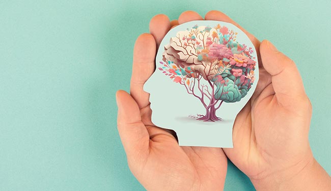 Hands holding a head with a brain of flowers - emotional support and recovery concept