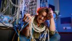 computer engineer wrapped in wires and cables in server room