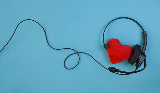A red heart with a call centre headset on it - on a blue background