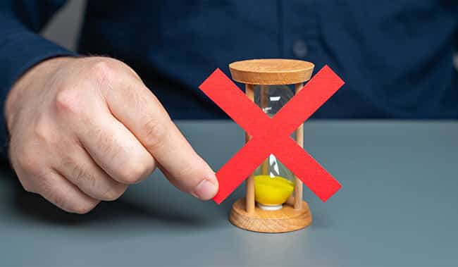 A man holds a red cross on top of an hourglass.