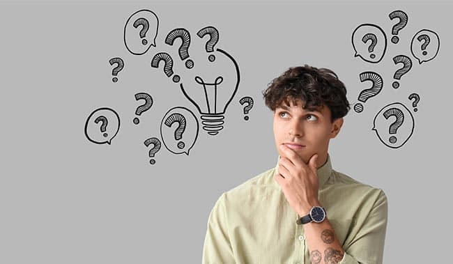 Thoughtful young man and drawn question marks on grey background with space for text
