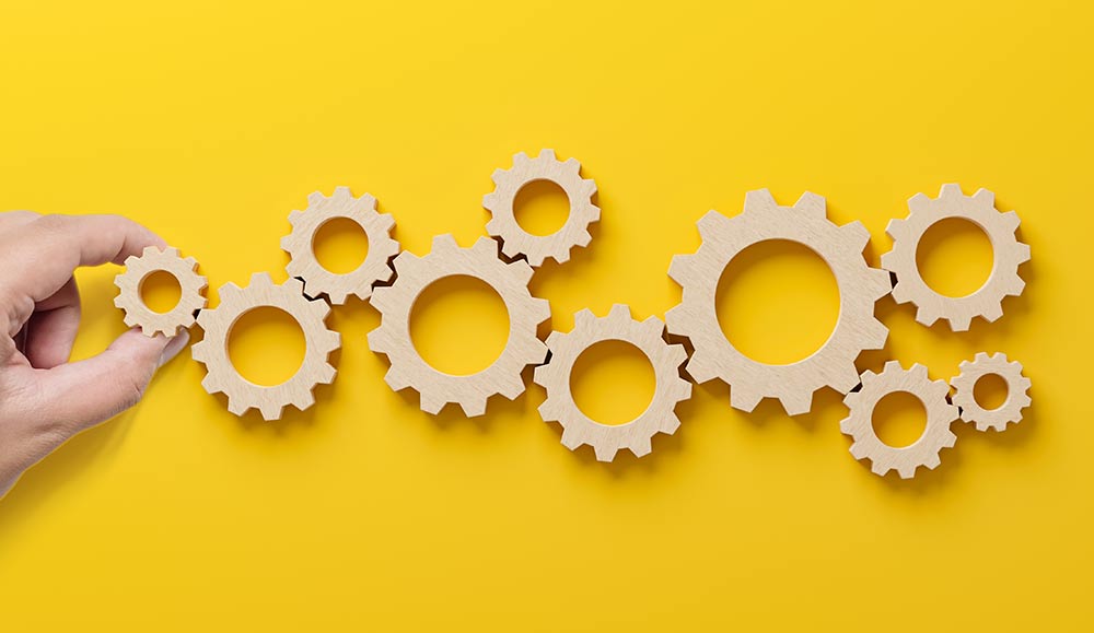 A hand placing cogs - technology adoption and implementation concept