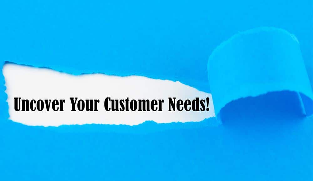Text Uncover Your Customer Needs appearing behind torn paper.