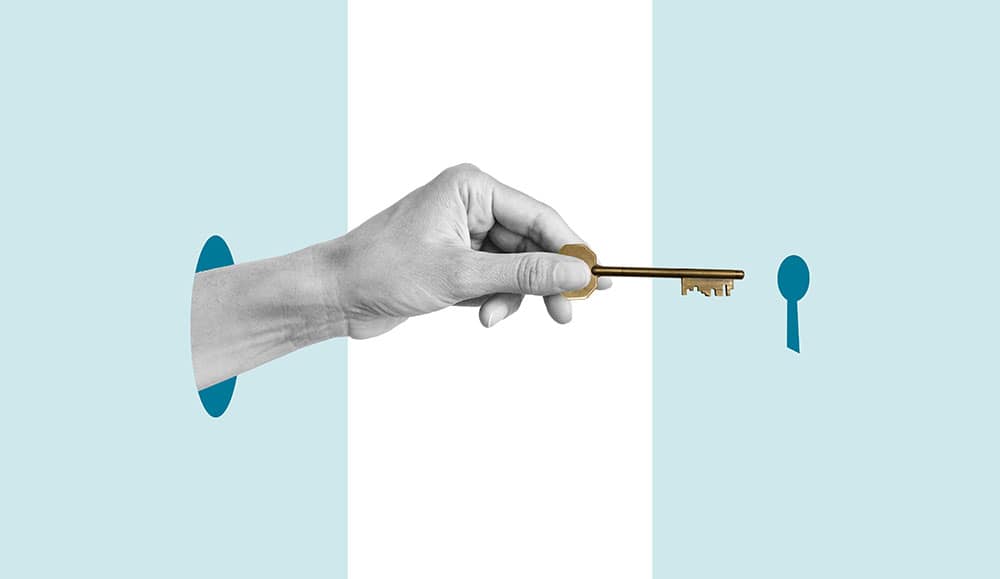 A hand holding a key heading towards a keyhold